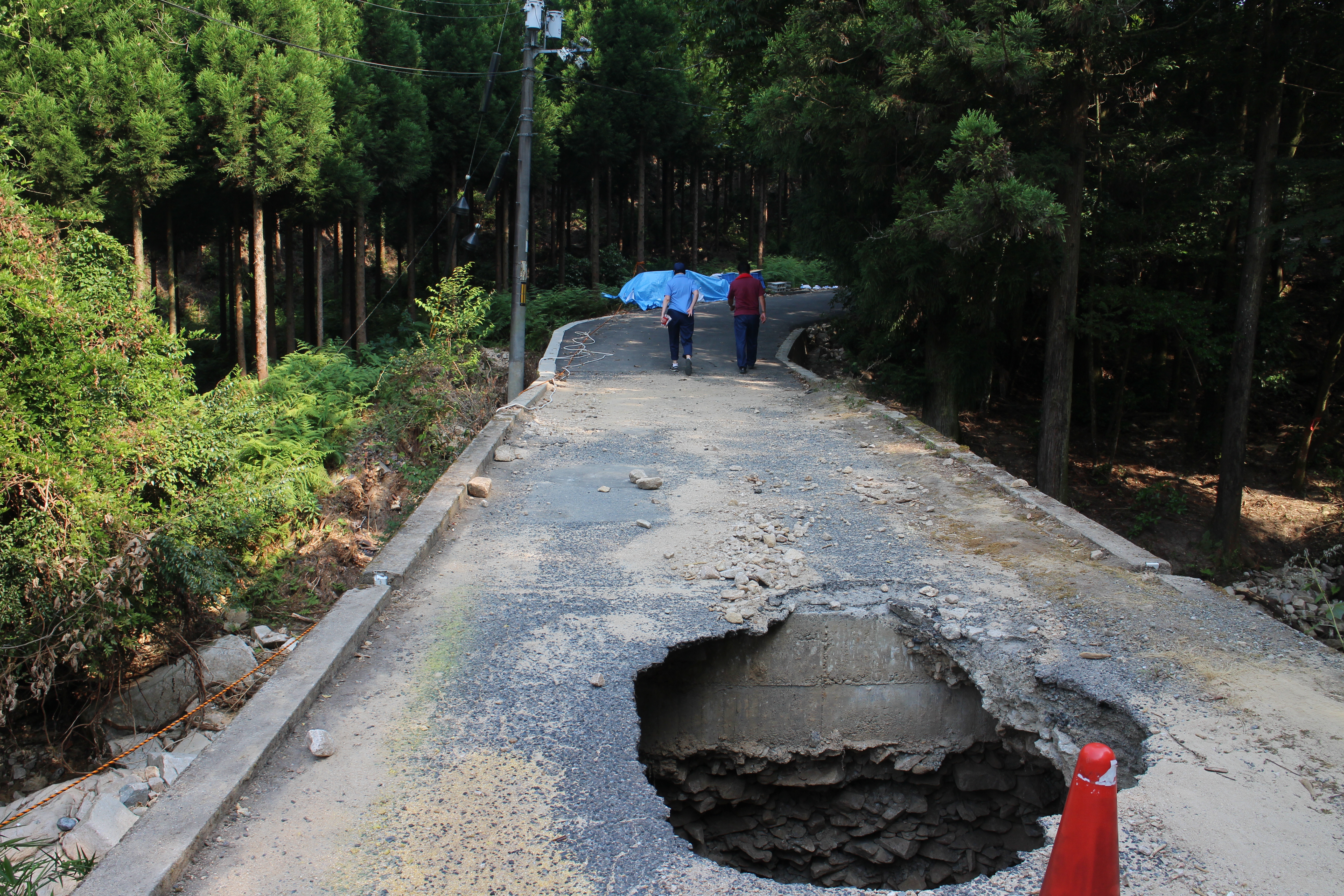 橋に穴が開き車は通れないことから、徒歩で山を登っての視察地へ向かう