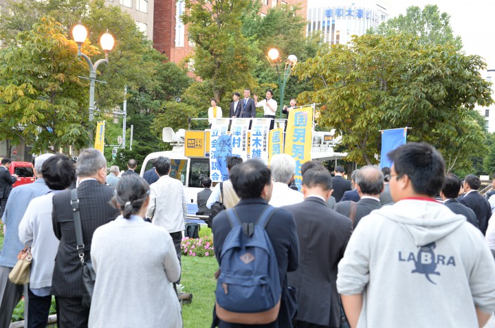 夕暮れ時の大通公園での演説に聞き入る